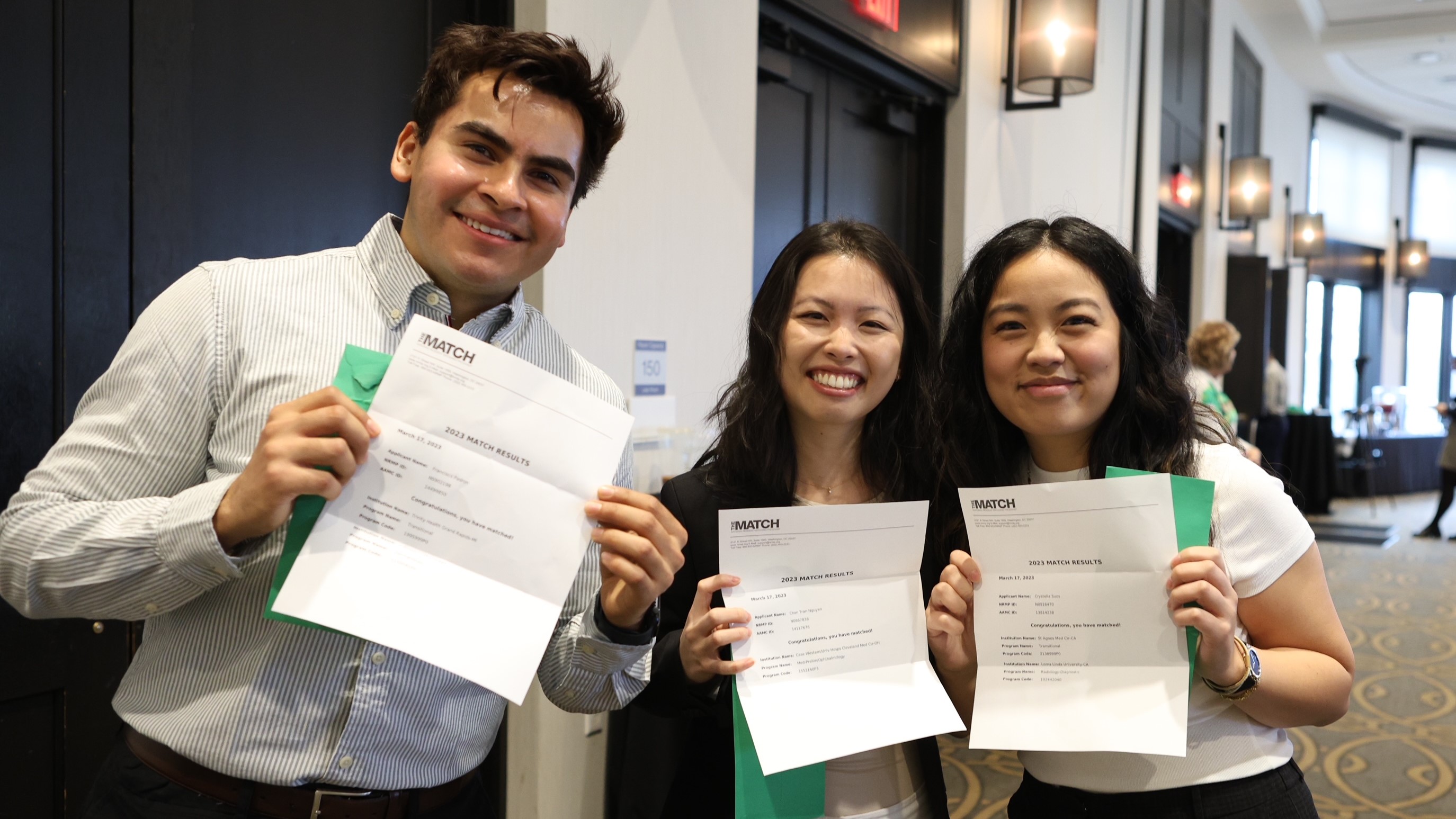 Three medical students holding their Match Day envelopes